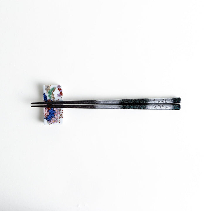 A pair of chopsticks with a gold and silver gradient design.