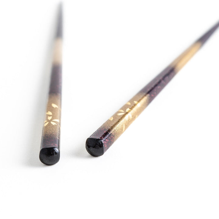 A pair of chopsticks with a gold and silver gradient design.