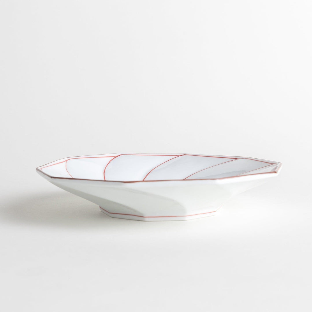 White luncheon plate with a petal design outlined in blue or red and bowl shape, featuring a subtle brown rim.