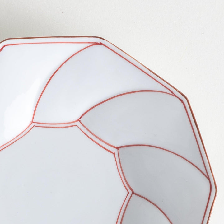 White luncheon plate with a petal design outlined in blue or red and bowl shape, featuring a subtle brown rim.