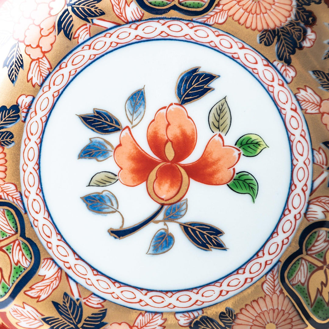 A dessert plate with a central floral design, bordered by intricate multicolored patterns and traditional motifs in gold and blue.