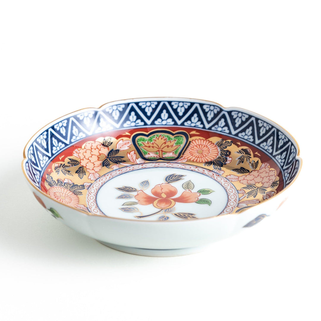 A dessert plate with a central floral design, bordered by intricate multicolored patterns and traditional motifs in gold and blue.