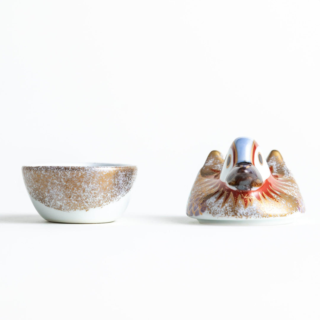 A small ceramic condiment bowl shaped like a drake, with gold accents and intricate painted details.