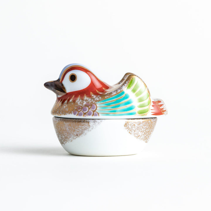 A small ceramic condiment bowl shaped like a drake, with gold accents and intricate painted details.