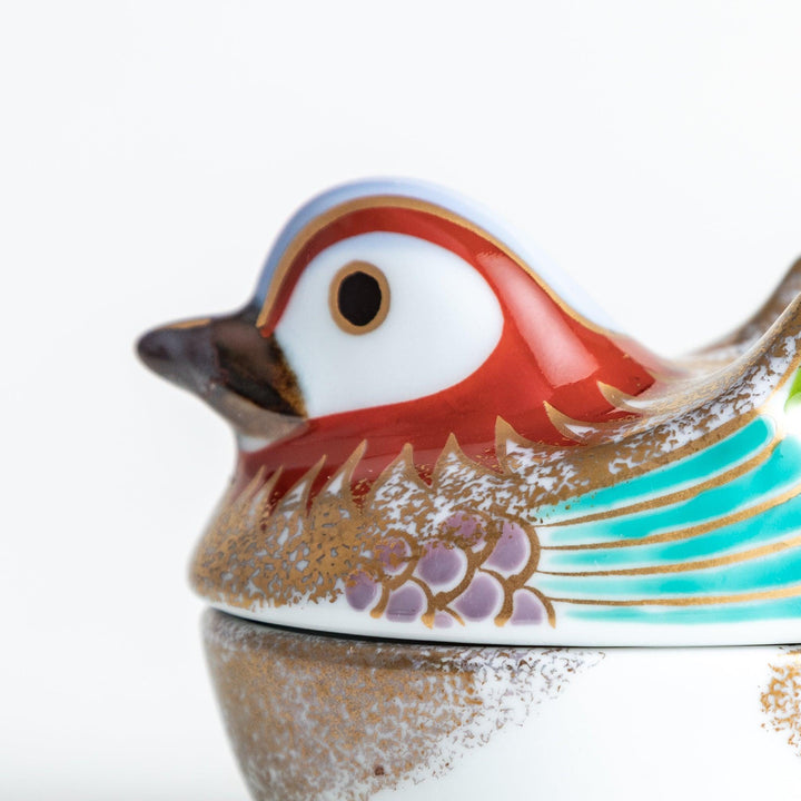 A small ceramic condiment bowl shaped like a drake, with gold accents and intricate painted details.