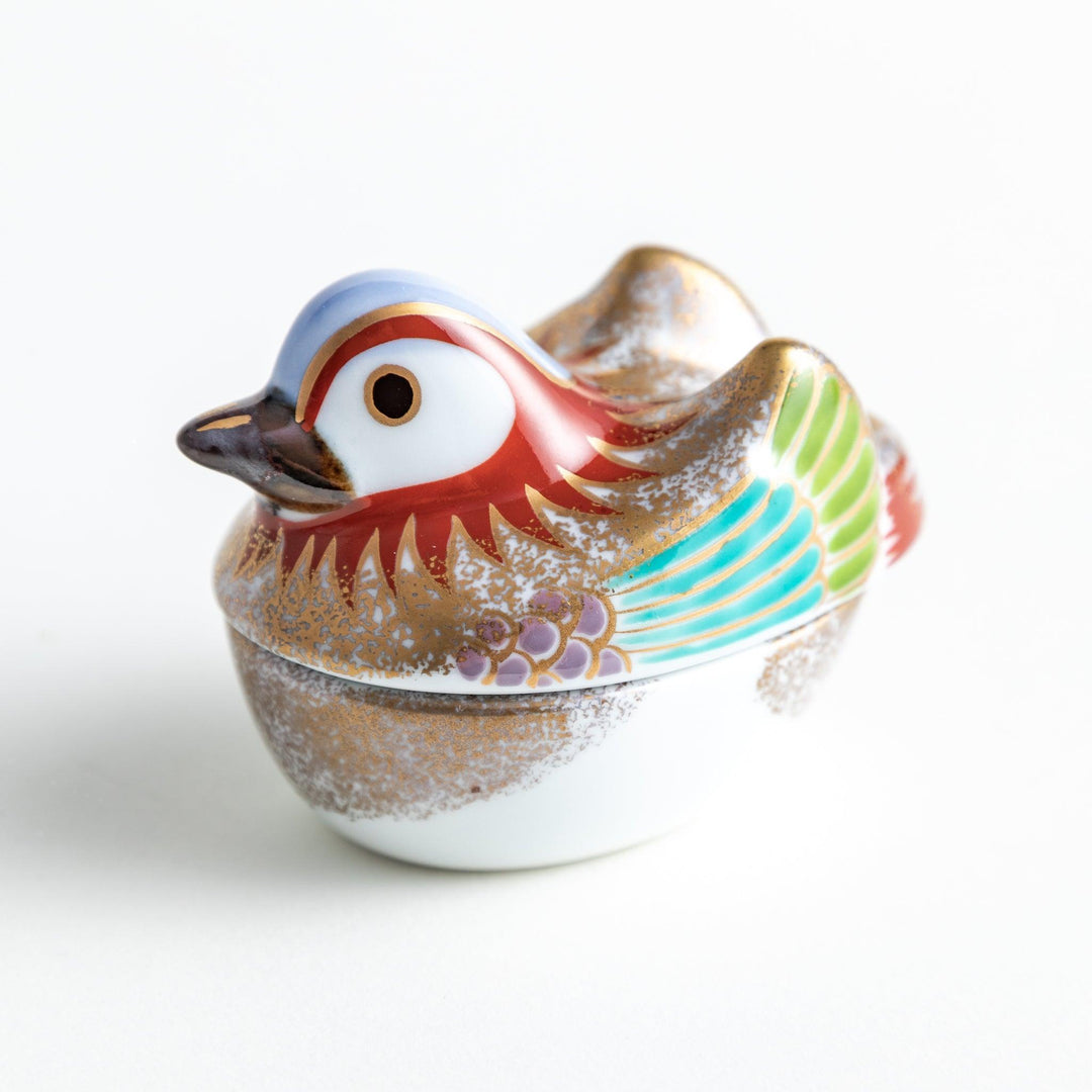 A small ceramic condiment bowl shaped like a drake, with gold accents and intricate painted details.