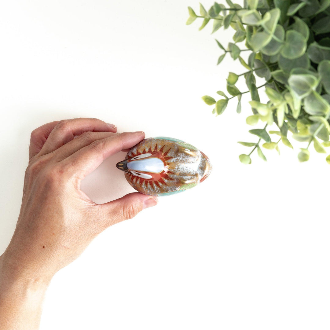 A small ceramic condiment bowl shaped like a drake, with gold accents and intricate painted details.