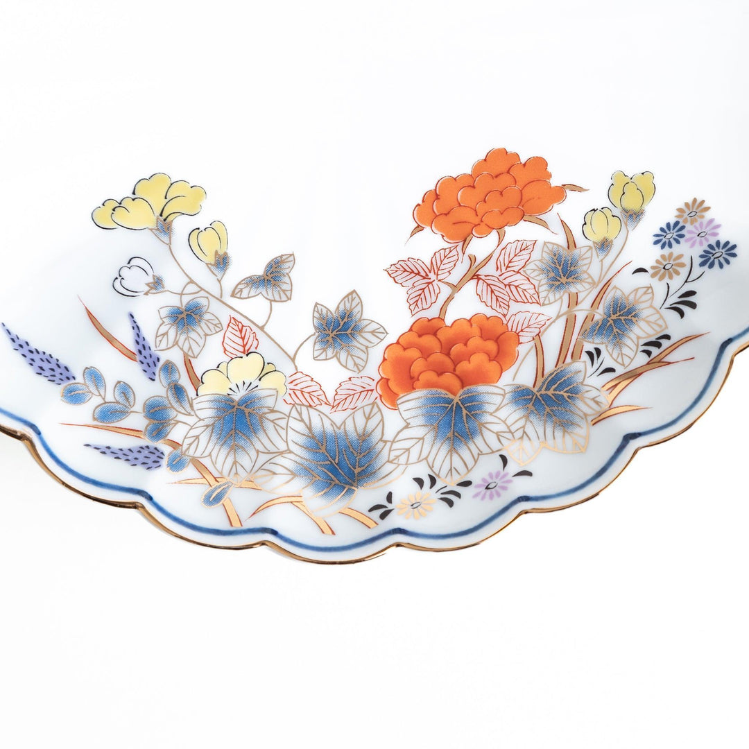 A round salad plate with scalloped edges, featuring delicate floral designs in red, yellow, and blue, with a branch of wisteria hanging from the top.