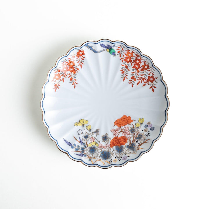 A round salad plate with scalloped edges, featuring delicate floral designs in red, yellow, and blue, with a branch of wisteria hanging from the top.