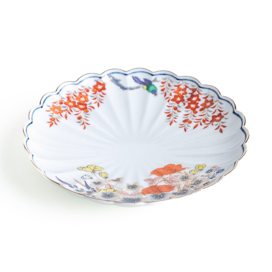 A round salad plate with scalloped edges, featuring delicate floral designs in red, yellow, and blue, with a branch of wisteria hanging from the top.