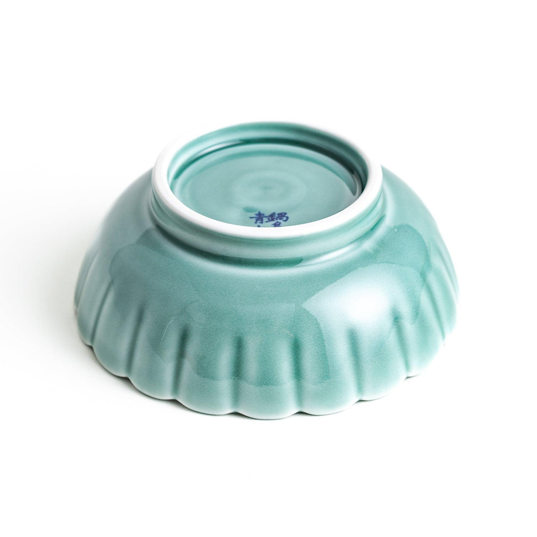 A small green cereal bowl with a scalloped edge and a blue and white wave pattern in the center.