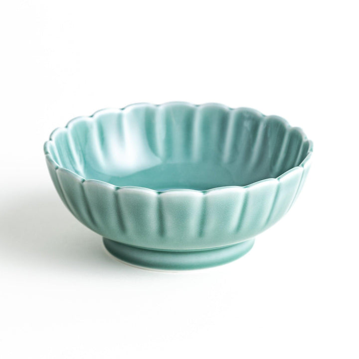 A small green cereal bowl with a scalloped edge and a blue and white wave pattern in the center.