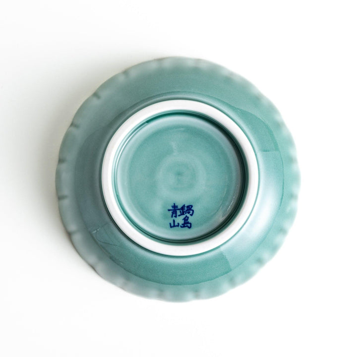 A small green cereal bowl with a scalloped edge and a blue and white wave pattern in the center.