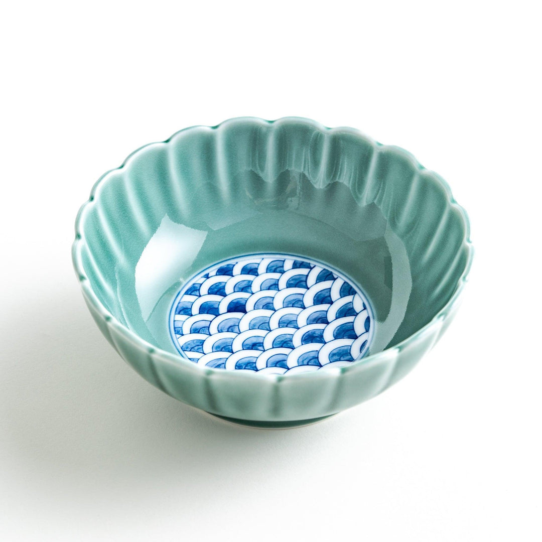 A small green cereal bowl with a scalloped edge and a blue and white wave pattern in the center.