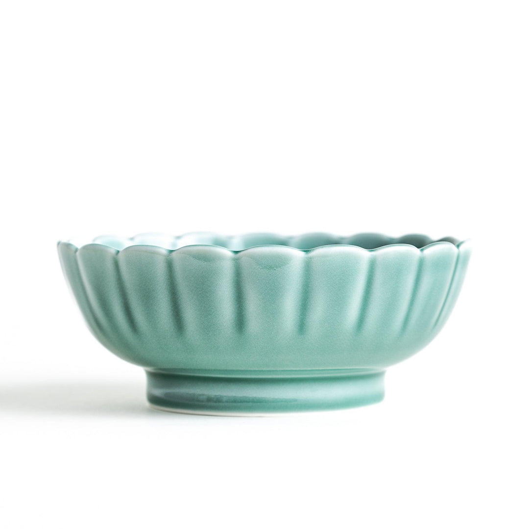 A small green cereal bowl with a scalloped edge and a blue and white wave pattern in the center.