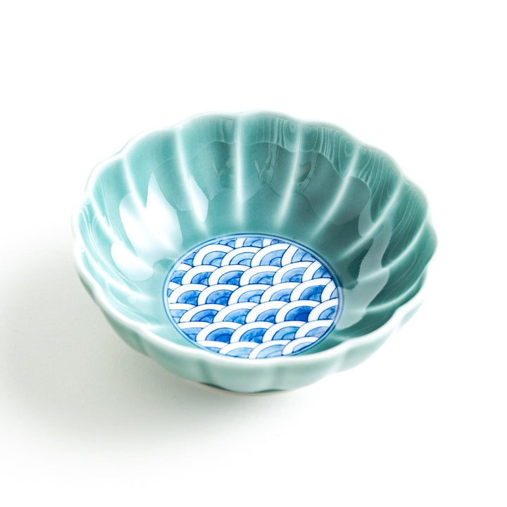 A small green cereal bowl with a scalloped edge and a blue and white wave pattern in the center.