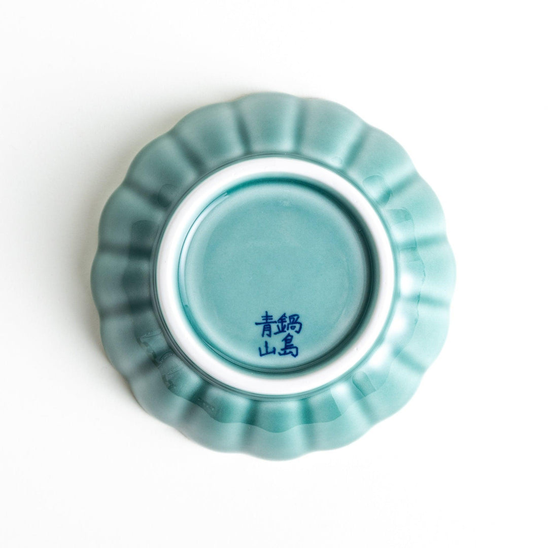 A small green cereal bowl with a scalloped edge and a blue and white wave pattern in the center.