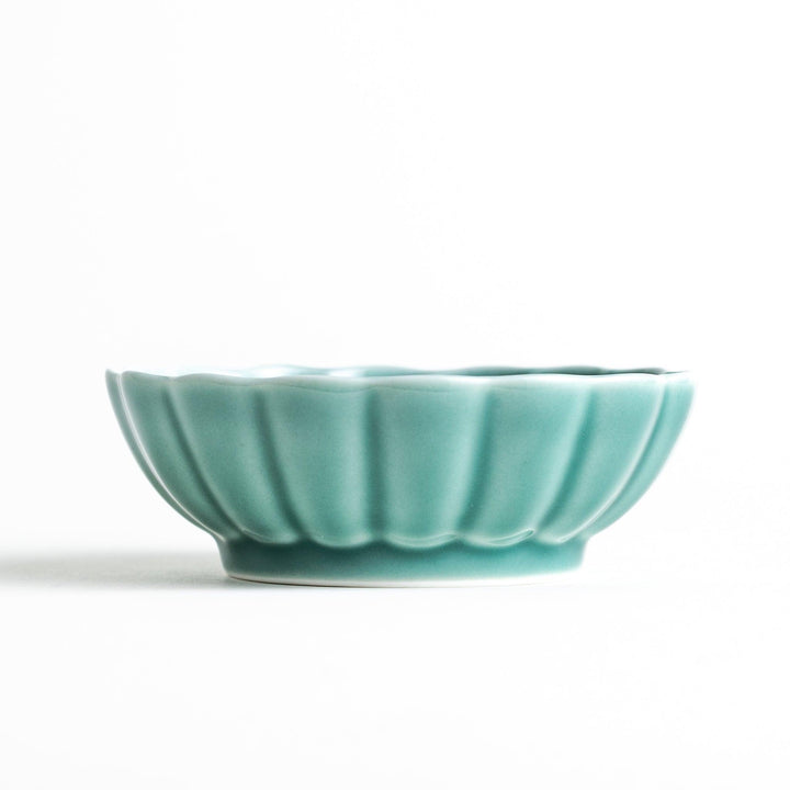 A small green cereal bowl with a scalloped edge and a blue and white wave pattern in the center.