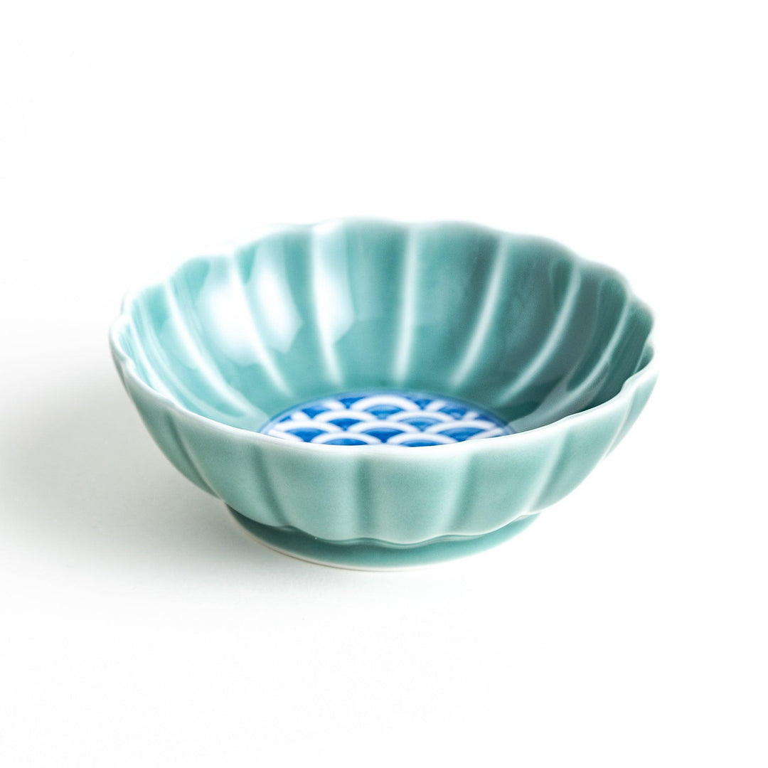 A small green cereal bowl with a scalloped edge and a blue and white wave pattern in the center.