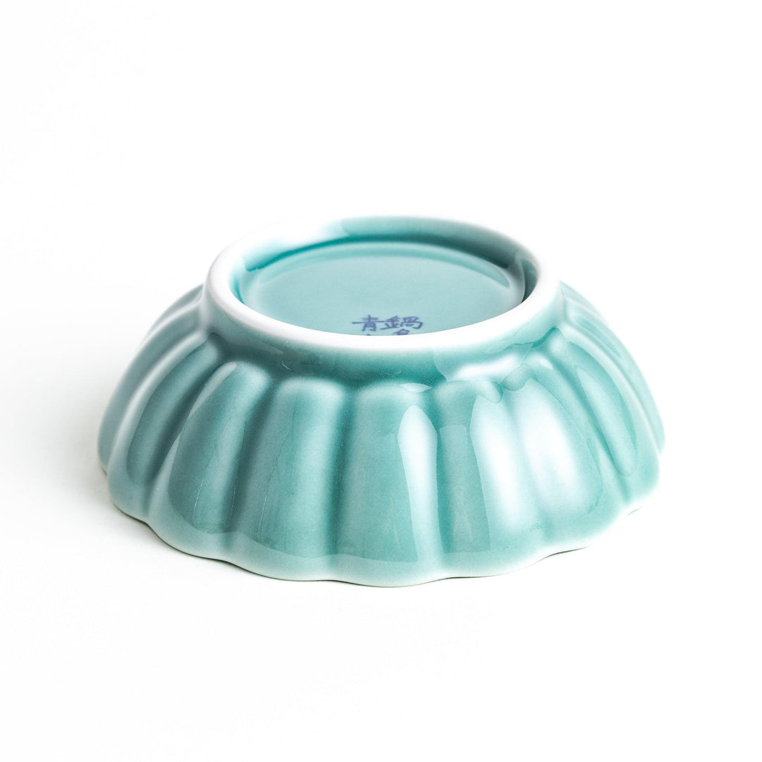 A small green cereal bowl with a scalloped edge and a blue and white wave pattern in the center.