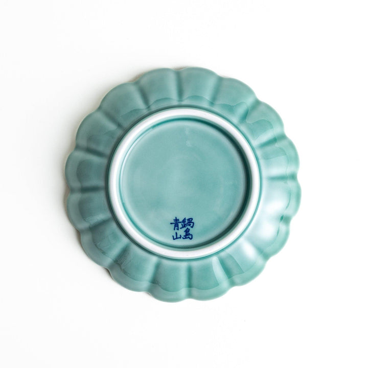 A scalloped-edged green plate with a blue and white wave pattern in the center.