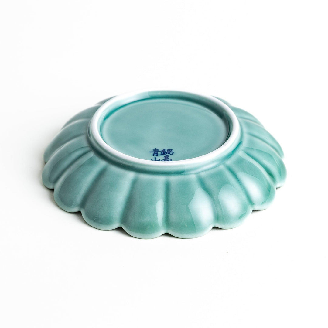 A scalloped-edged green plate with a blue and white wave pattern in the center.