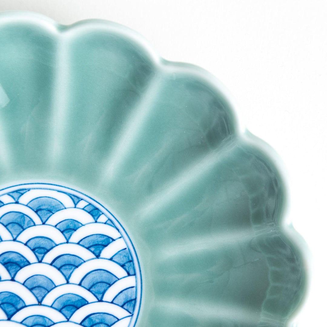 A scalloped-edged green plate with a blue and white wave pattern in the center.