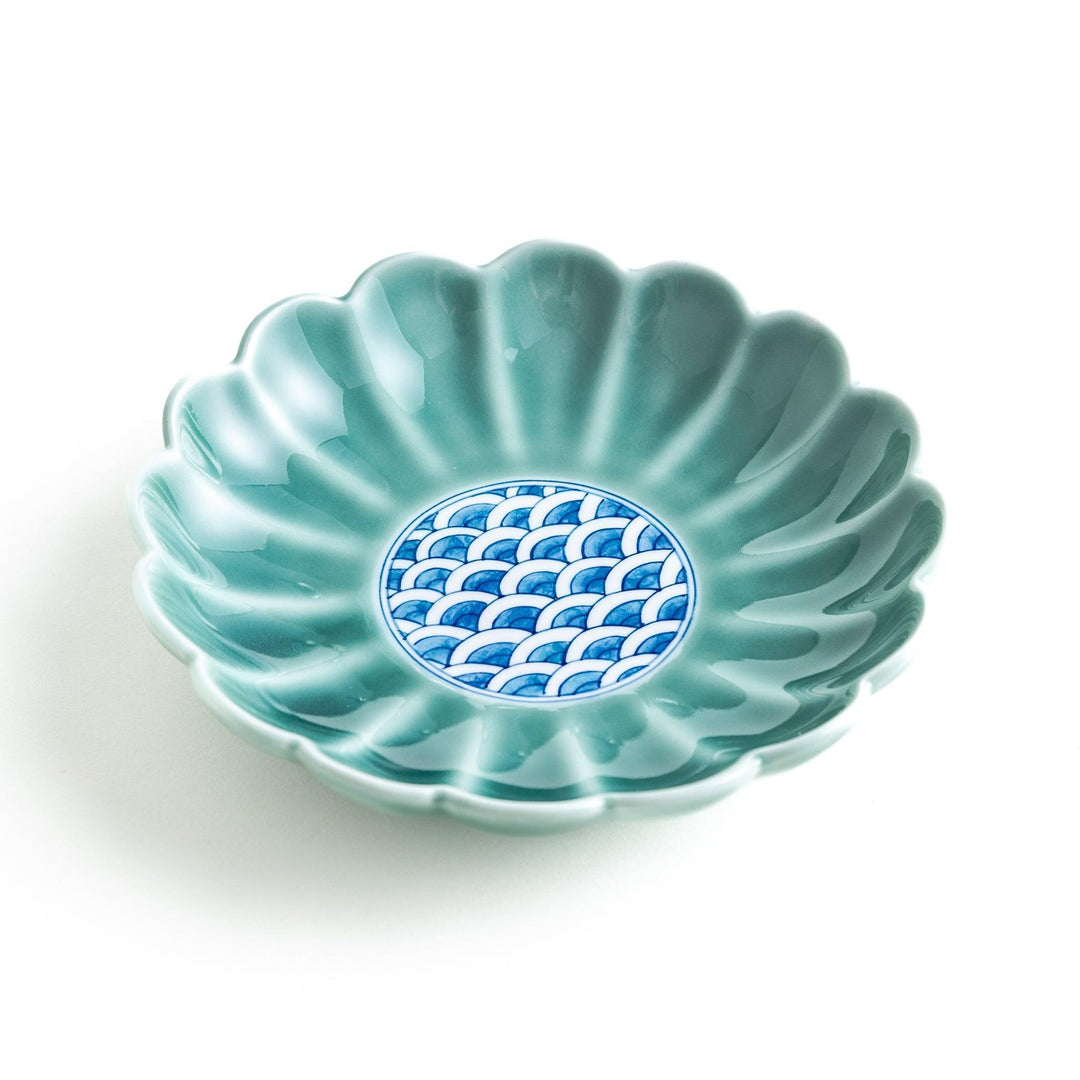 A scalloped-edged green plate with a blue and white wave pattern in the center.