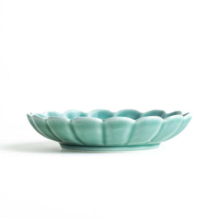 A scalloped-edged green plate with a blue and white wave pattern in the center.