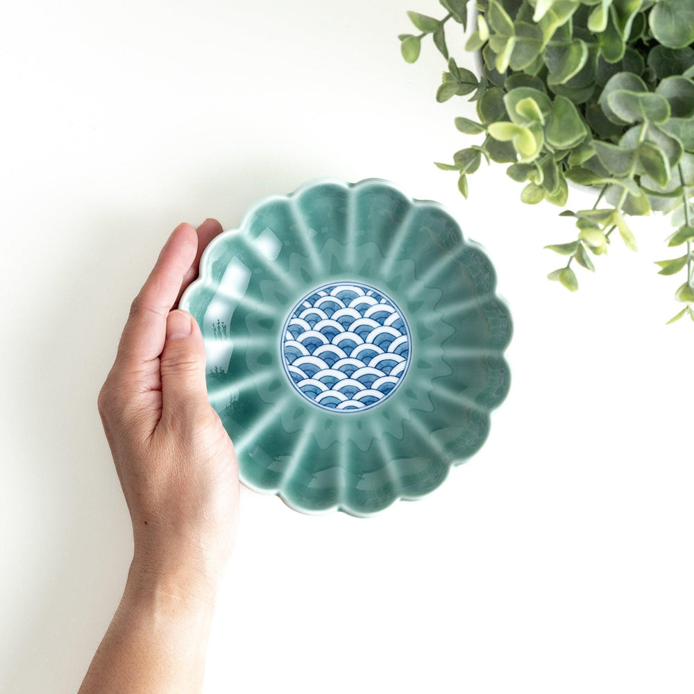 A scalloped-edged green plate with a blue and white wave pattern in the center.