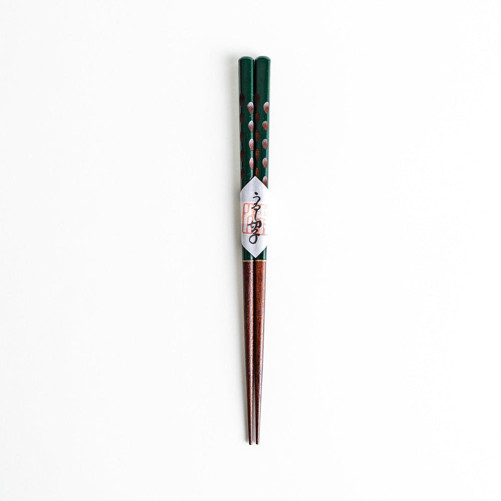 A pair of green-handled chopsticks with a detailed design near the top.