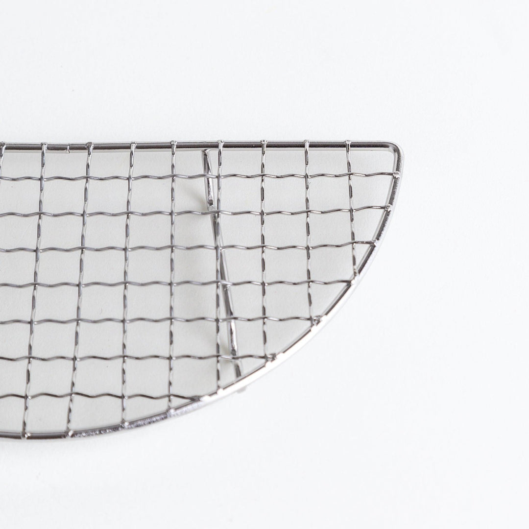 A semi-circular metal grilling rack, featuring a mesh pattern and designed to fit over a heat source for cooking.