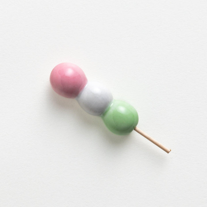 Ceramic chopstick rests shaped like Japanese dango skewers with pink, white, and green balls.