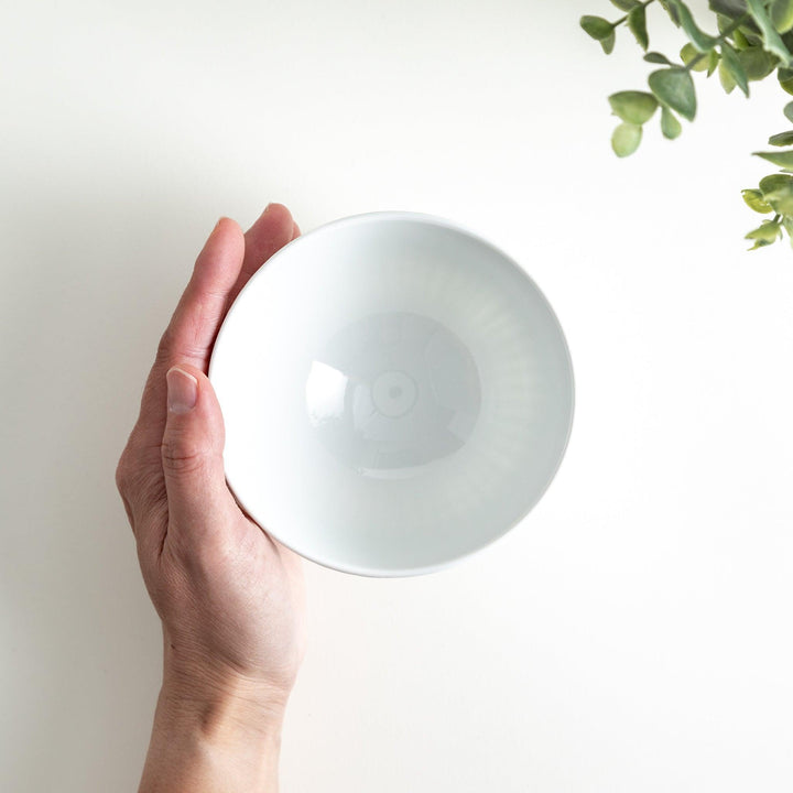 A white ceramic bowl featuring a linear carved design.