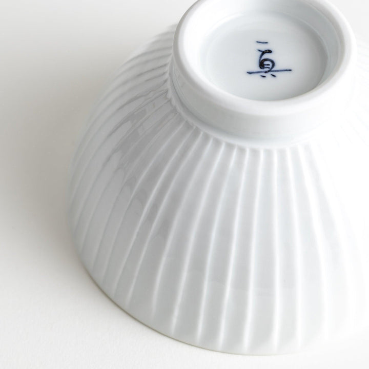 A white ceramic bowl featuring a linear carved design.