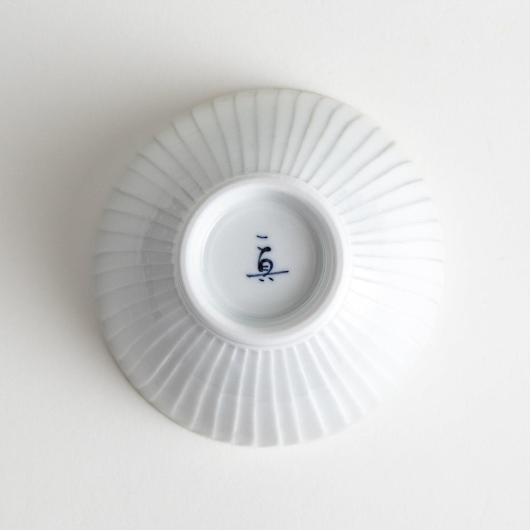 A white ceramic bowl featuring a linear carved design.