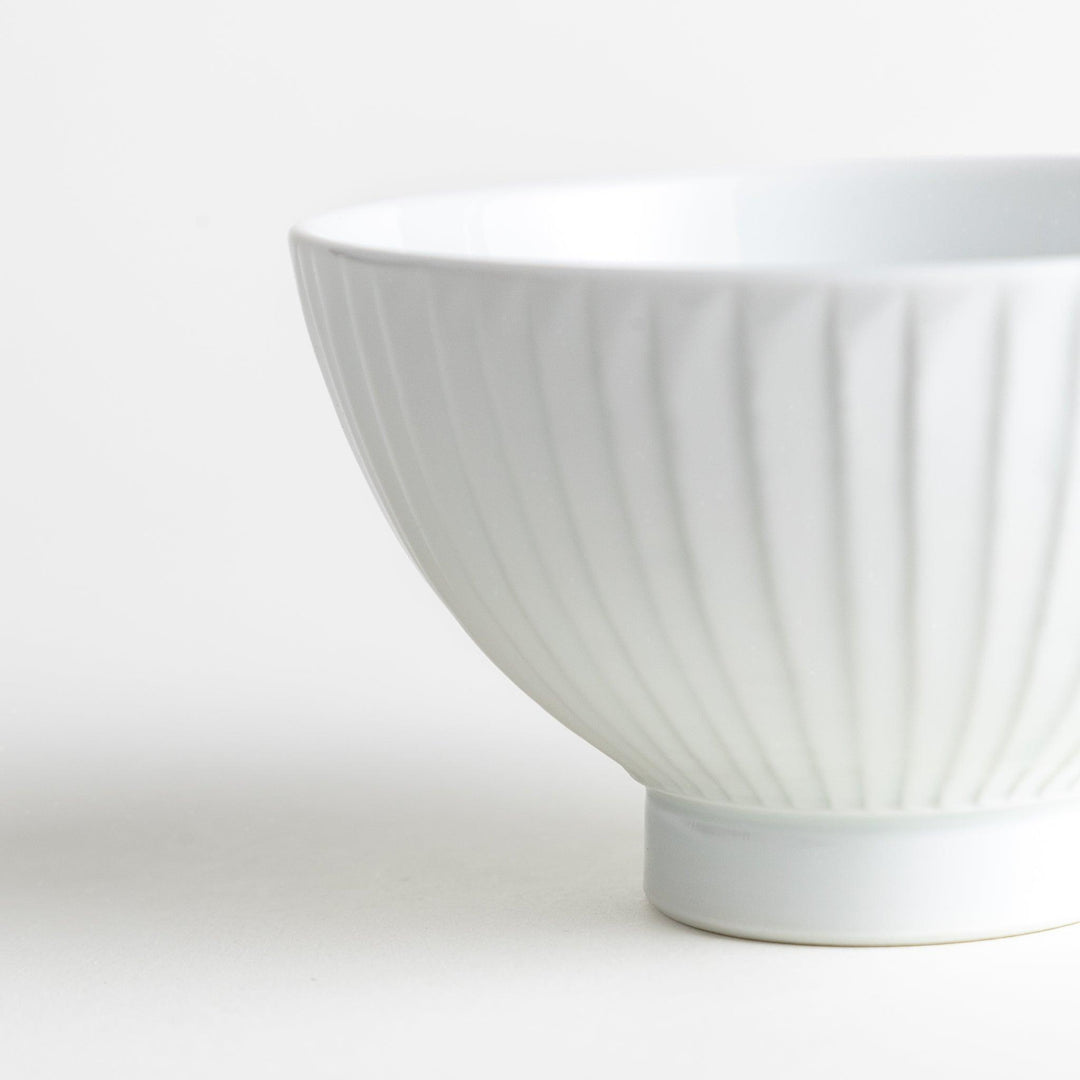 A white ceramic bowl featuring a linear carved design.