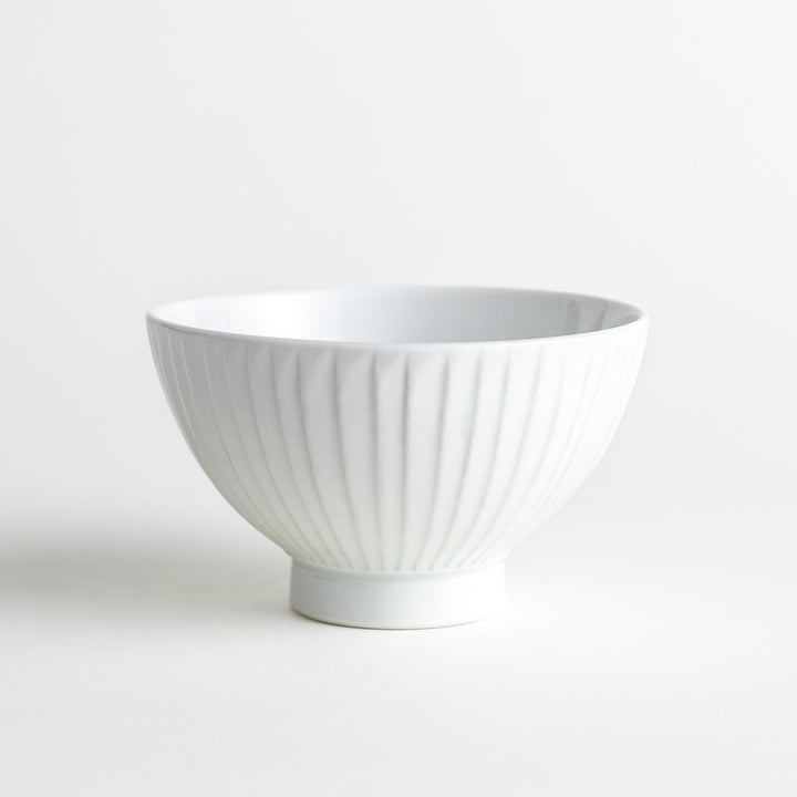 A white ceramic bowl featuring a linear carved design.