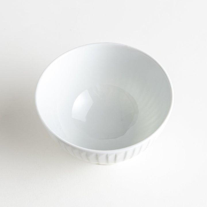 A white ceramic bowl featuring a linear carved design.