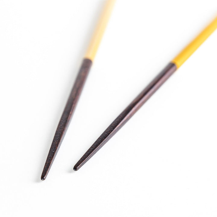 Chopsticks in different colors—white, yellow, olive green, navy blue, and dark brown—with wooden lower halves.