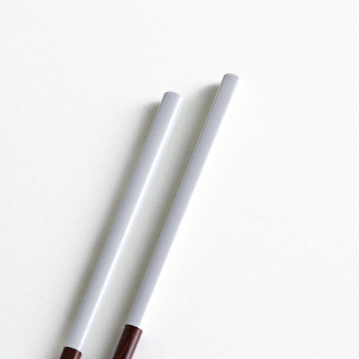 Chopsticks in different colors—white, yellow, olive green, navy blue, and dark brown—with wooden lower halves.