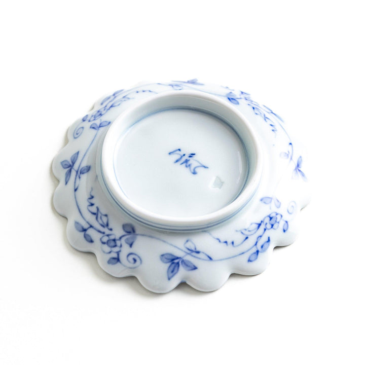 White plate with blue floral patterns and scalloped edges.