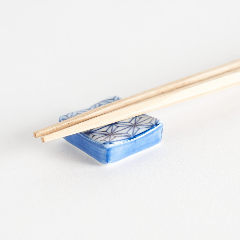 A blue and white geometric patterned square-shaped ceramic chopstick rest.