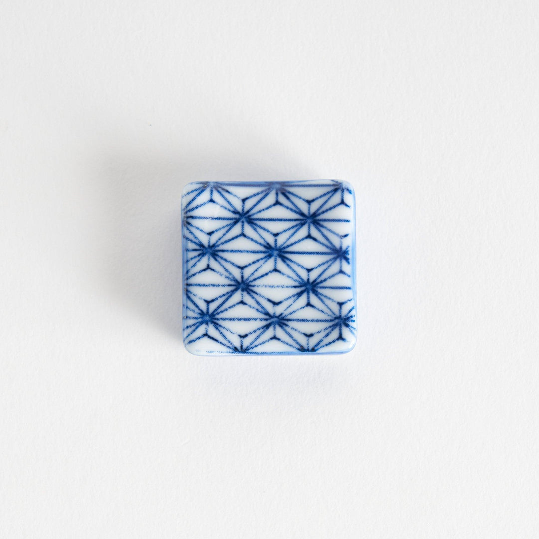 A blue and white geometric patterned square-shaped ceramic chopstick rest.