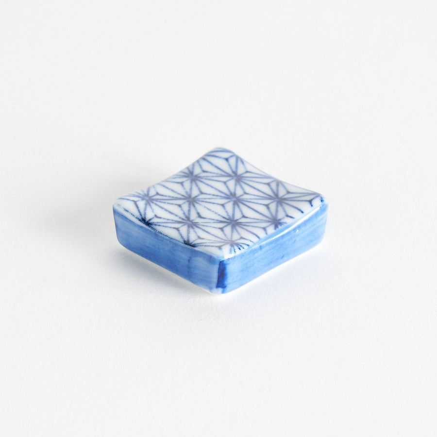 A blue and white geometric patterned square-shaped ceramic chopstick rest.