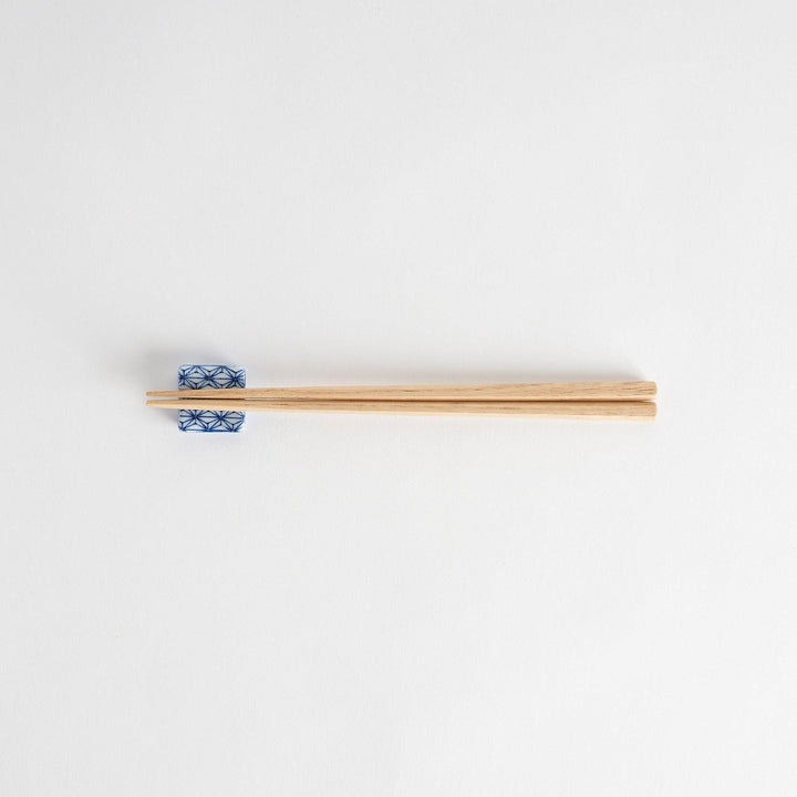 A blue and white geometric patterned square-shaped ceramic chopstick rest.