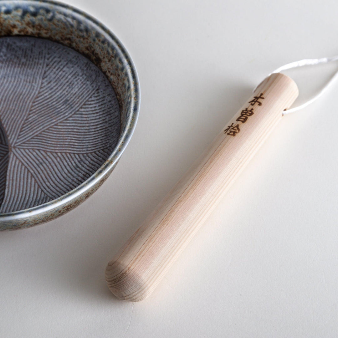 A wooden pestle, with Japanese characters engraved on the side.