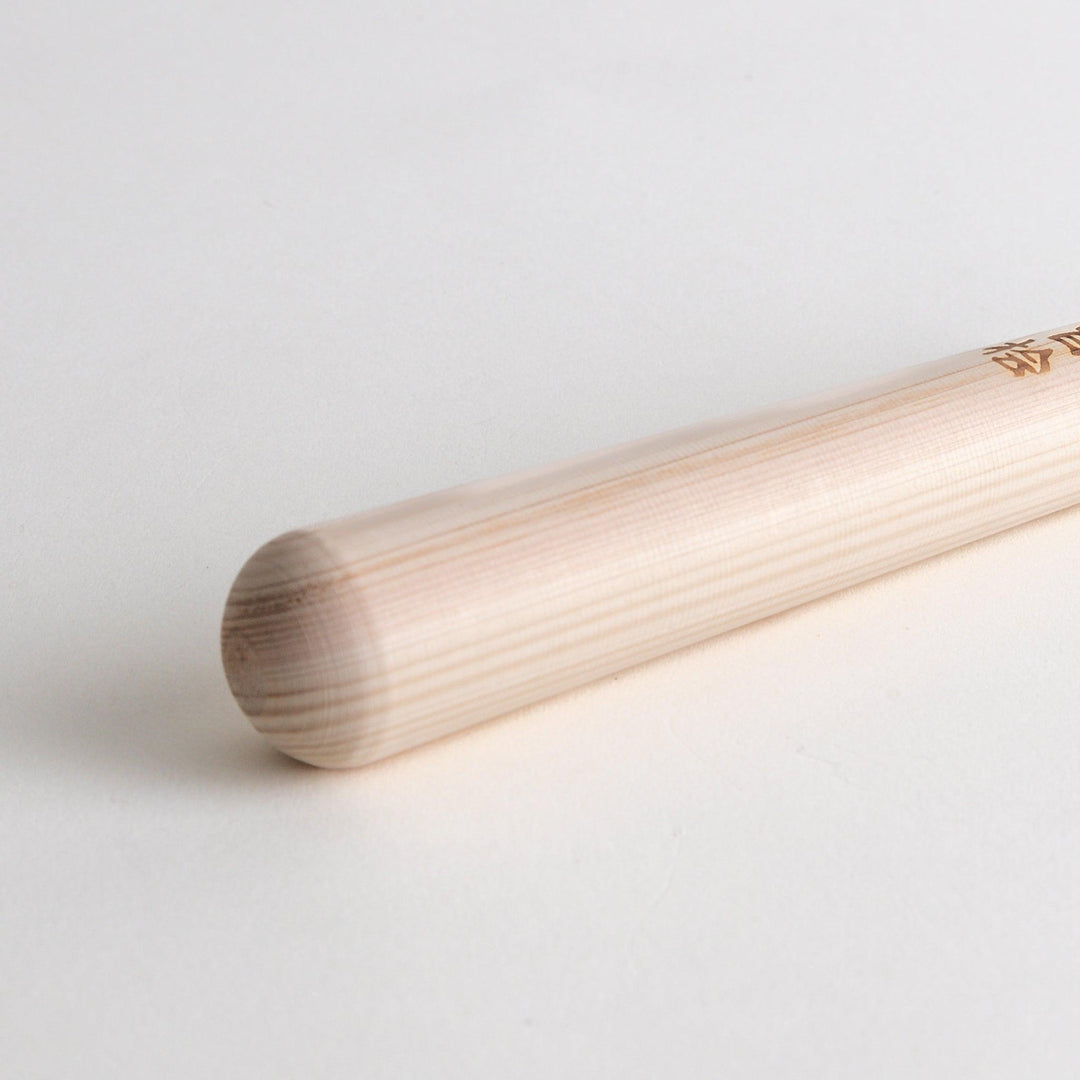 A wooden pestle, with Japanese characters engraved on the side.