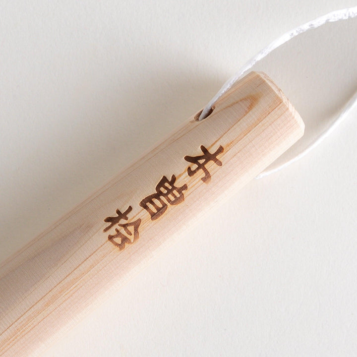 A wooden pestle, with Japanese characters engraved on the side.