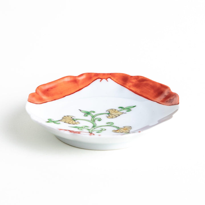 A scalloped Mount Fuji ceramic plate with a red border and an elegant floral design in soft green and yellow tones.